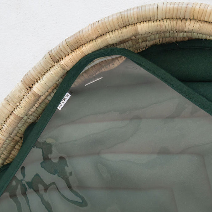 Close-up of a clear changing mat on top of a changing padding in a lala palm changing basket on a plain background