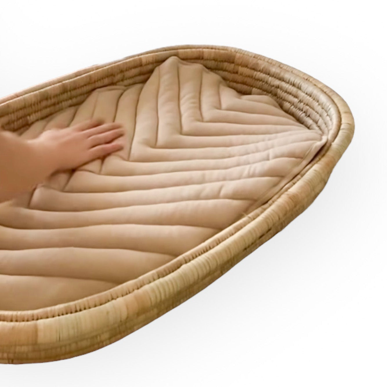 A fudge color, quilted cotton changing pad/mat in a changing basket with a simple aesthetic design, laid flat on a white surface.